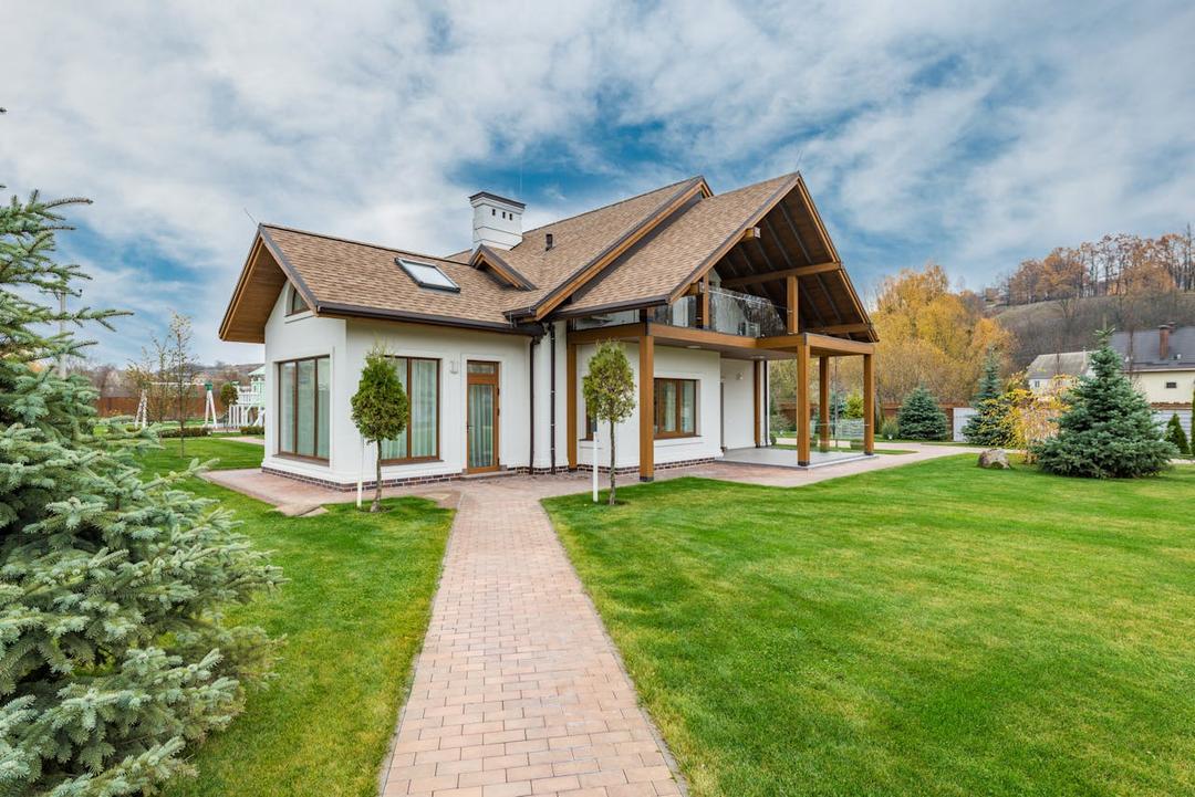 A house surrounded by a well-maintained garden with mowed lawn and trimmed trees